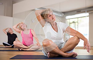 Elderly woman making stretching exercises in fitness studio