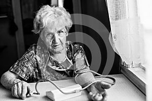 An elderly woman measures arterial pressure.