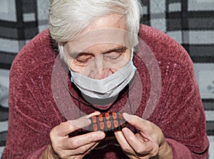 Elderly woman in a medical mask. The tablets