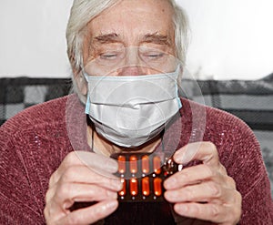 Elderly woman in a medical mask. The tablets