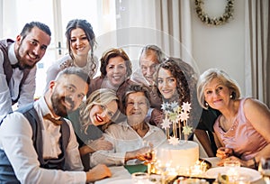 An elderly woman with multigeneration family celebrating birthday on indoor party.