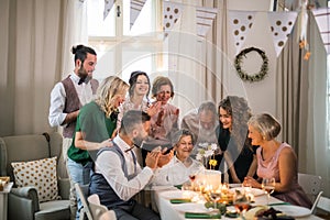 An elderly woman with multigeneration family celebrating birthday on indoor party.