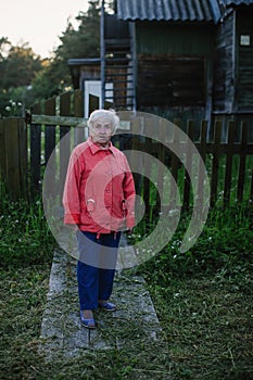 Elderly woman near her house in the village. Nature.