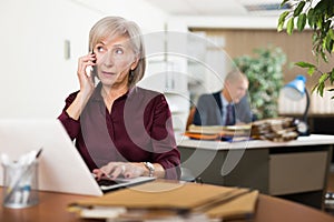 Elderly woman office worker talking on phone