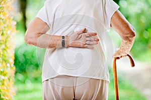 Elderly woman outdoors with back pain