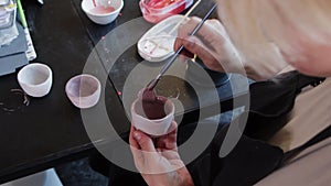 An elderly woman painting ceramic mug in dusty purple