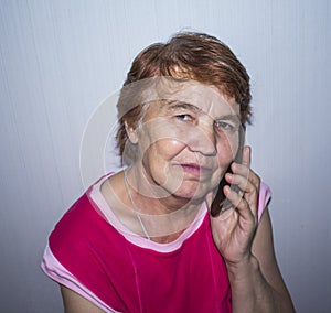 An elderly woman with a phone near her ear photo