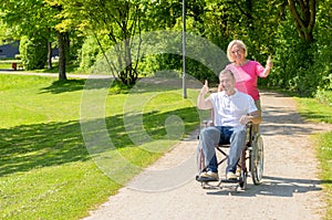 Elderly woman in pink blouse pushes wheel chair