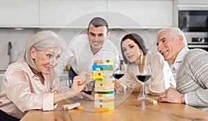 Elderly woman playing jenga with relatives during family gathering