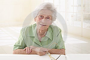 An elderly woman portrait holding glasses in her living room