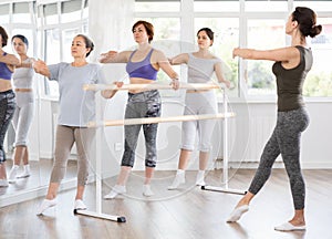 Elderly woman practicing battement tendu in beginners ballet class