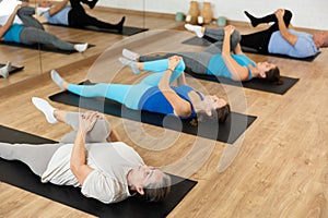 Elderly woman practicing pilates on mat in gym area
