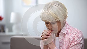 Elderly woman praying to God, asking for mercy and help, Christian tradition