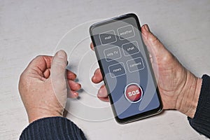 An elderly woman presses the SOS help button on the smartphone. Hands of an old man. Panic button, Technology