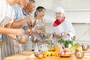 Elderly woman professional chef conducting group culinary courses