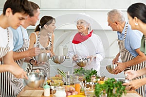 Elderly woman professional chef conducting group culinary courses