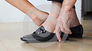 Elderly woman putting on shoes with care giver.