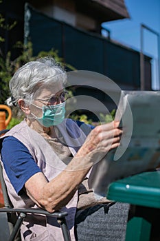 elderly woman reading newspaper during coronavirus epidemic quarantine