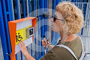 An elderly woman reading a text in braille. Button for calling help for people with disabilities.