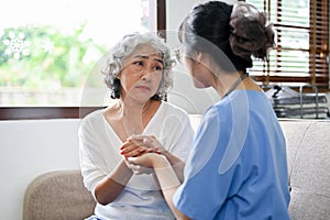 An elderly woman is reassured by a doctor. holding an aged female`s hands to comfort photo