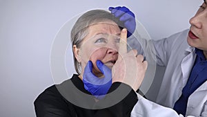 An elderly woman at the reception of a facial plastic surgeon. Consultation on the removal of age wrinkles on the face. The doctor
