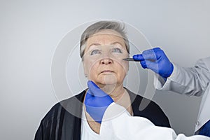 An elderly woman at the reception of a facial plastic surgeon. Consultation on the removal of age wrinkles on the face. The doctor