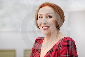 Elderly woman with red hair looking at the camera and smiling