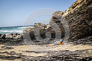 Elderly woman relaxing by rocks in Zambujeira Do Mar, Alentejo, Portugal photo