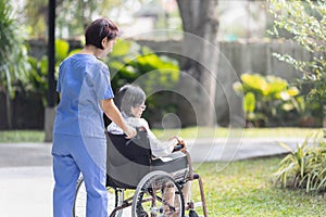 Elderly woman relaxing on wheelchair in backyard with caregiver