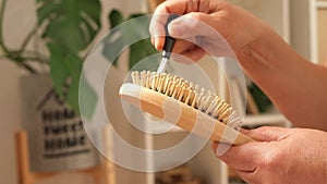 An elderly woman removes long gray hair that has fallen out from comb. Hair care at any age.