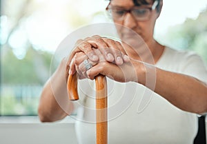 .elderly woman resting her hands on her walking stick while relaxing at home.