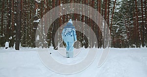 An elderly woman rides classic skis through a winter forest