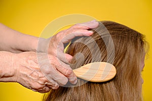 Elderly woman's hand combing granddaughter's hair