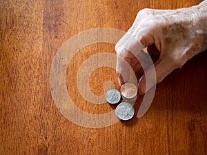 Elderly Woman`s Wrinkled Hand Stacking Pennies, Nickels and Dime