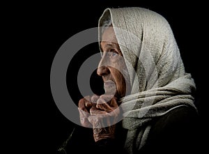 Elderly woman with scarf on black background, studio portrait
