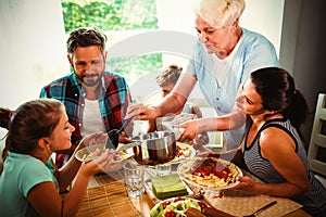 Elderly woman serving meal to her family