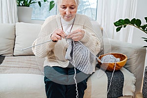 An elderly woman of seventy years, is embroidering with knitting needles