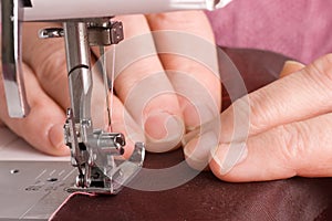 Elderly woman sews on the sewing machine