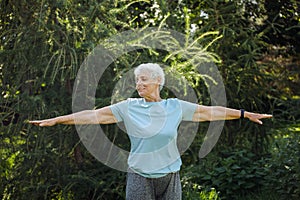 Elderly woman with short hair practicing yoga and tai chi outdoors. Old female meditating.