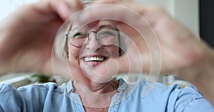 Elderly woman showing symbol of love with joined fingers