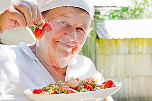 Elderly woman shows strawberry