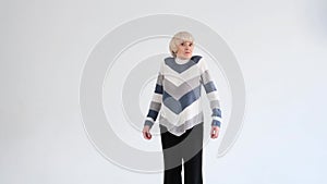 an elderly woman shrugs her shoulders on a white background.