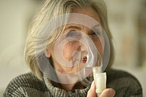 Elderly woman is sick and uses an inhaler