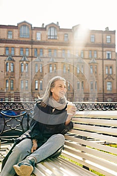 Elderly woman sitting on bench in autumn park