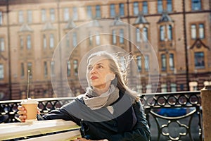 Elderly woman sitting on bench in autumn park