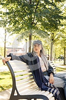 Elderly woman sitting on bench in autumn park