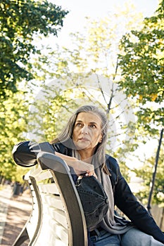 Elderly woman sitting on bench in autumn park