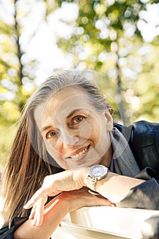 Elderly woman sitting on bench in autumn park