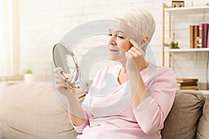 Elderly Woman Sitting on Couch Looking Into Mirror