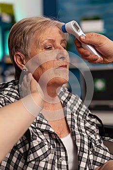 Elderly woman sitting having her temperature taken